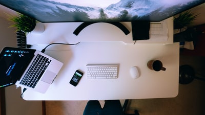 打开智能手机旁的笔记本电脑和白色电脑桌上的苹果键盘和魔法鼠标